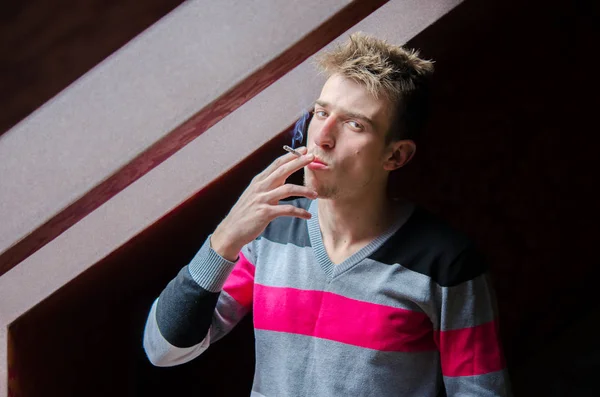 Молодой человек, курящий утреннюю сигарету у окна, будучи худым — стоковое фото