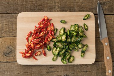 Biber biber kırmızı ve dilimlenmiş yeşil ve bıçak kesme tahtaları üzerinde 