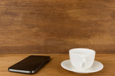 Kupa, fincan kahve ve br önünde ahşap tahta üzerinde akıllı telefon
