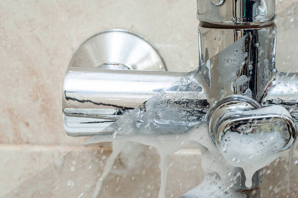 The difference before and after washing off a special detergent for chrome surfaces. Bathroom faucet.