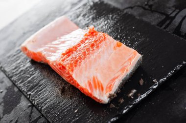 Taze kırmızı balıklı bifteğin yarısı ıslak bir taş standında duruyor.