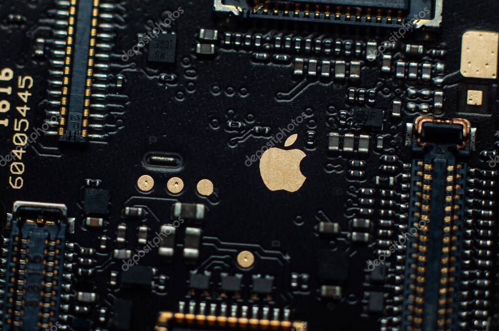Kiev, Ukraine - May 6, 2020: Image of a golden apple on the iphone se phone motherboard. Detached loopback connectors. Close-up, macro shot.