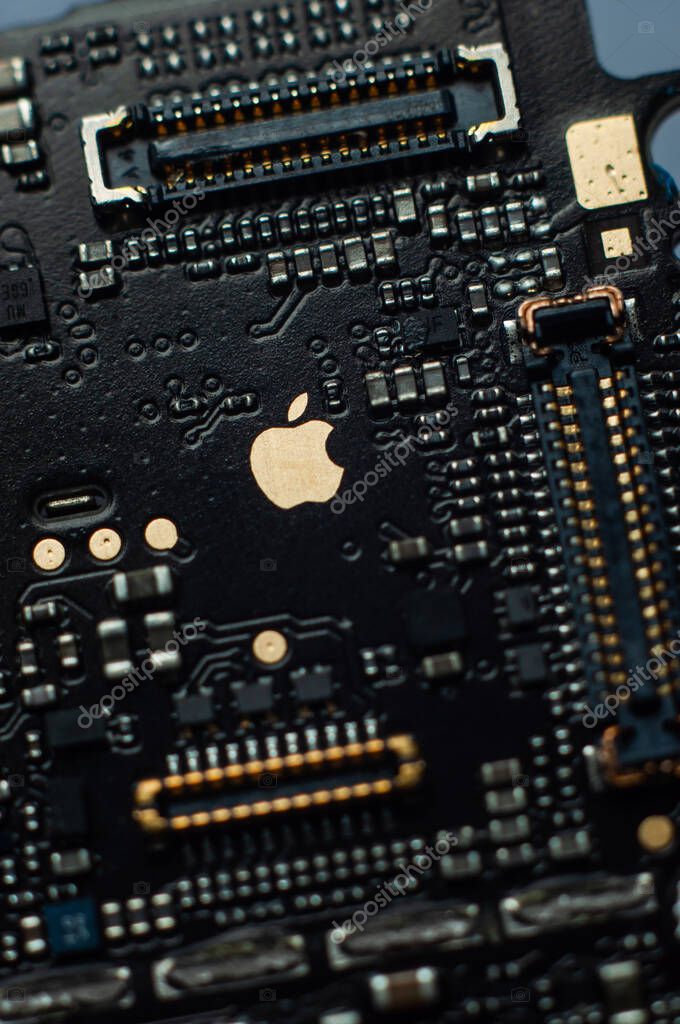 Kiev, Ukraine - May 6, 2020: Image of a golden apple on the iphone se phone motherboard. Detached loopback connectors. Close-up, macro shot.