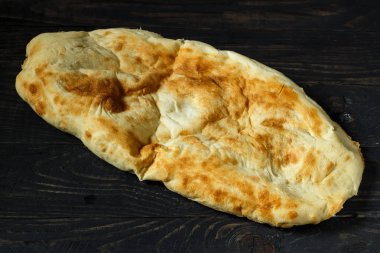 Koyu renkli ahşap masada Pita