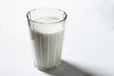 Beyaz arka planda bir bardak süt. Yakın plan.