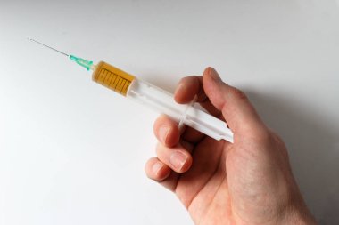 El şırıngayı beyaz arka planda tutuyor.