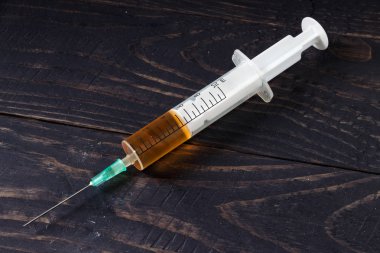 Ahşap arka planda yakın plan ilaçlı şırınga.