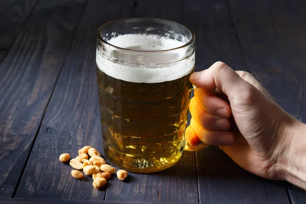 The hand of three has a glass of beer and peanut nuts