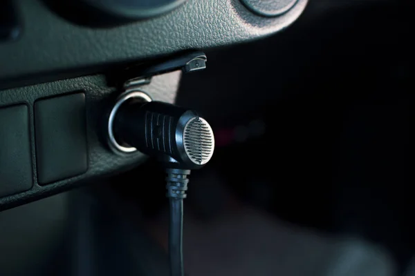 Die 12 Volt-Steckdose im Auto mit dem Adapterstecker an der Steckdose halten. — Stockfoto