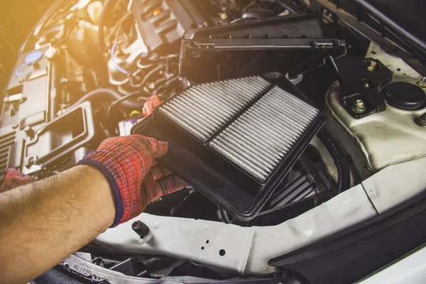 Car air filter in a hand of mechanic man is installing into air filter socket of car engine,Automotive part concept.