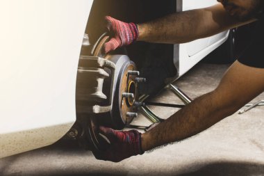 Tamirci el, araba tamirhanesinde disk frenlerini ve arabanın kalibrelerini kontrol ediyor..