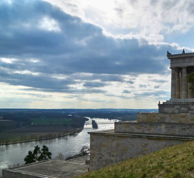 Genç kadın ile dramatik bulutlar bir terasta peyzaj içine bakıyor