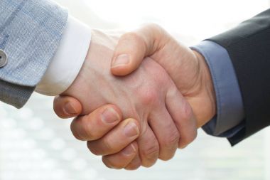Başarılı iş adamları el sıkışarak anlaşma yapıyor.