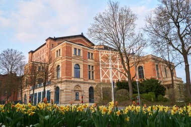 Bayreuth Wagner Festivali tiyatro günbatımında ön planda bahar çiçekleri ile.