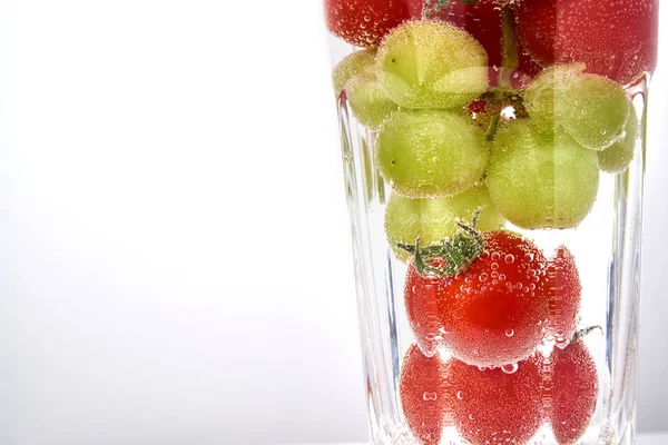 Pomidory cherry i winogron w glas z miejsca kopii waterwith. — Zdjęcie stockowe