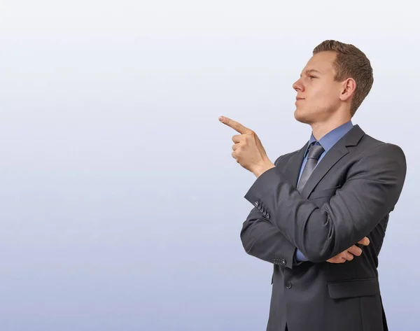 Young businessman points with his finger on the left side - isolated with copyspace. Sceptical, critical or analyzing expression for advertisement. — Stock Photo, Image
