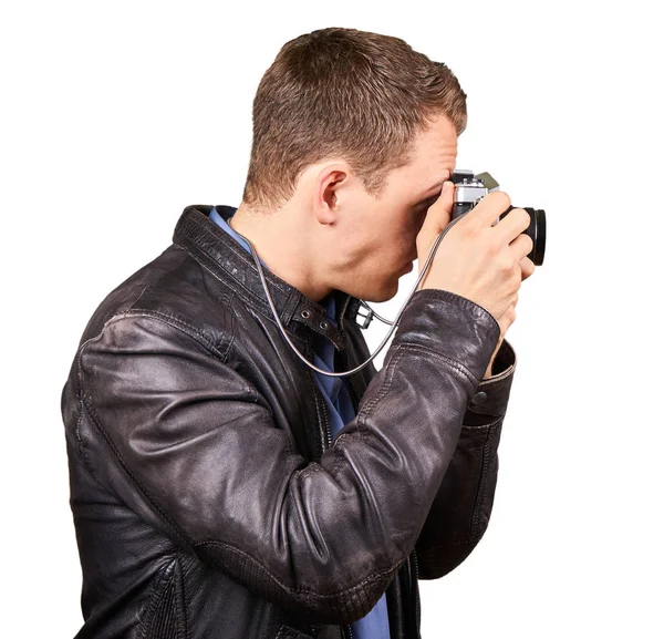 Zijaanzicht van een jonge man met een lederen jas een vintage camera maken van een foto - geïsoleerd. — Stockfoto