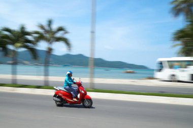 Nha Trang, Vietnam yakınındaki plaj önünde tanınmayan motobike sürücü. Bulanık çekimde ele geçirdi. Bir Turist otobüsü ile arka planda.