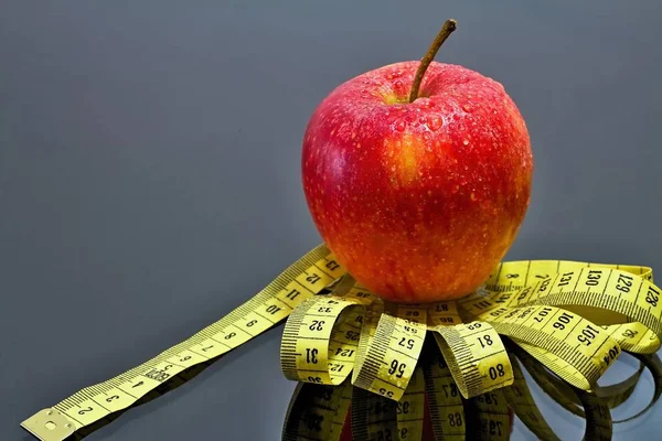 Fresh red apple with drops of water on a measuring tape with mirror reflection. — Stock Photo, Image