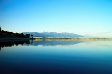 Düzey su Barajı Liptovska Mara Havranok Kilisesi ve Batı Tatras arka plan ile dağlar görüntüleyin. Güzel Slovak sahne.
