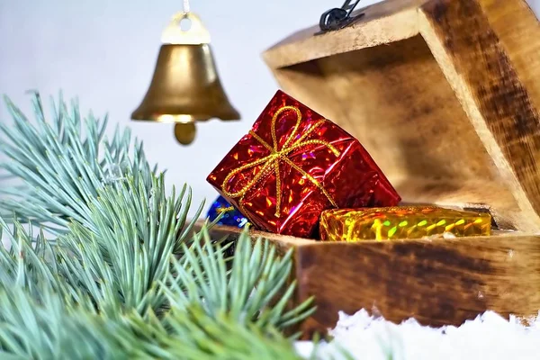 Weihnachtsgeschenk in roter Verpackung. Weihnachtsdekoration für den Weihnachtsgruß mit einer Truhe, einem Zweig Weißkiefer und einer Glocke. — Stockfoto