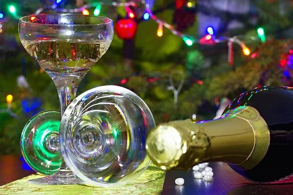 New Years Eve background. Champagne glasses and christmas tree lighting.