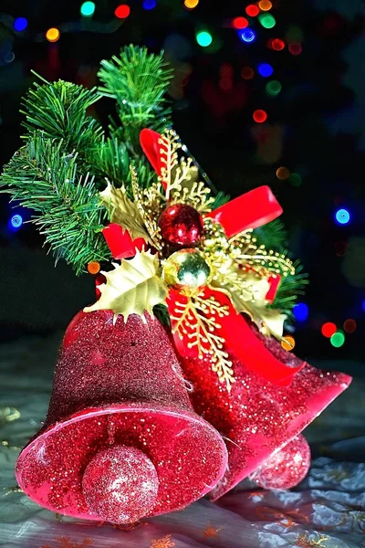 Weihnachtsglocken auf einem Tannenzweig mit Weihnachtsbeleuchtung Hintergrund. — Stockfoto