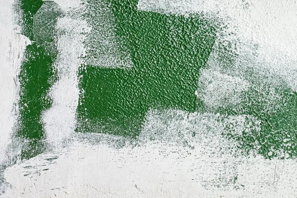 old concrete wall covered with textured plaster and painted with green paint. splashes of white paint and cracks, background for design