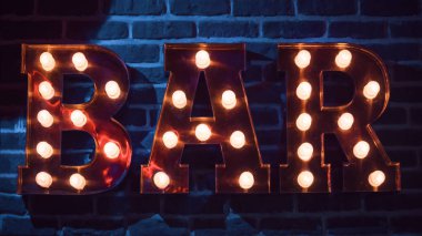 Tabela mavi tuğla duvar arka plan üzerinde kelime çubuklu. Harfleri akkor lambalar ile dekore edilmiştir.