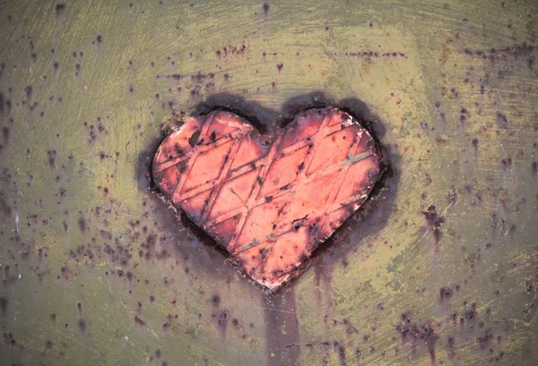 Metal heart on a metallic surface of green color