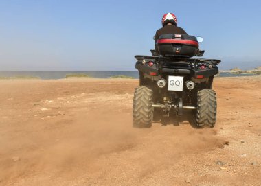 Bir adam bir kask içinde kum ATV sürme.
