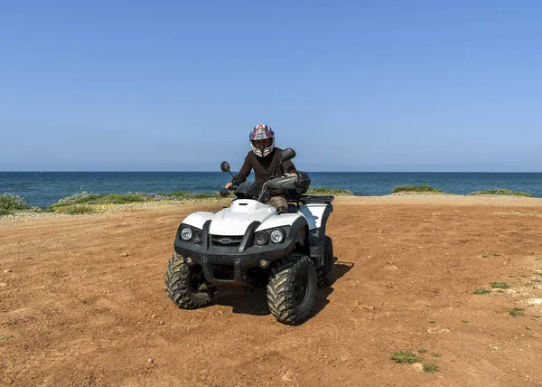 Un hombre montando ATV en arena en un casco . — Foto de Stock