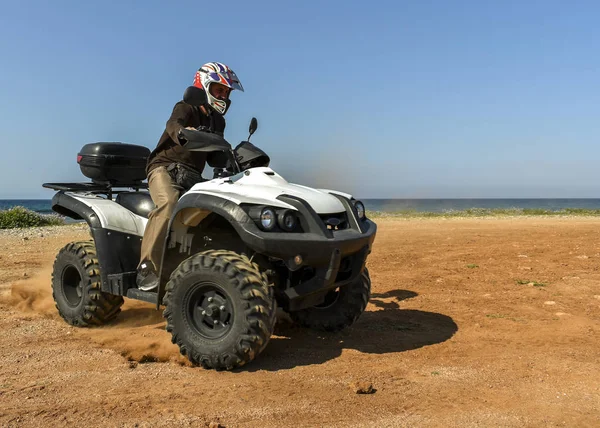 Un hombre montando ATV en arena en un casco . — Foto de Stock