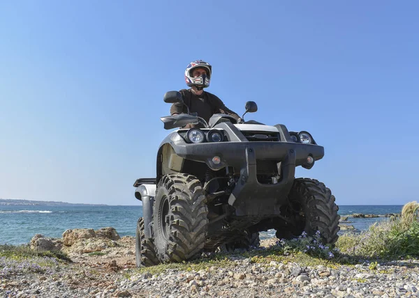 A man riding ATV in sand in a  helmet. — Stock Photo, Image