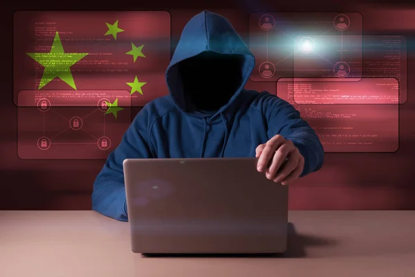 Hacker egy laptop előtt ülve, a háttérben a kínai digitális zászlaja — Stock Fotó