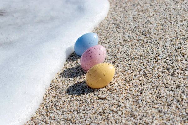 Coloridos huevos de Pascua en la playa en un día soleado. Concepto Pascua — Foto de Stock