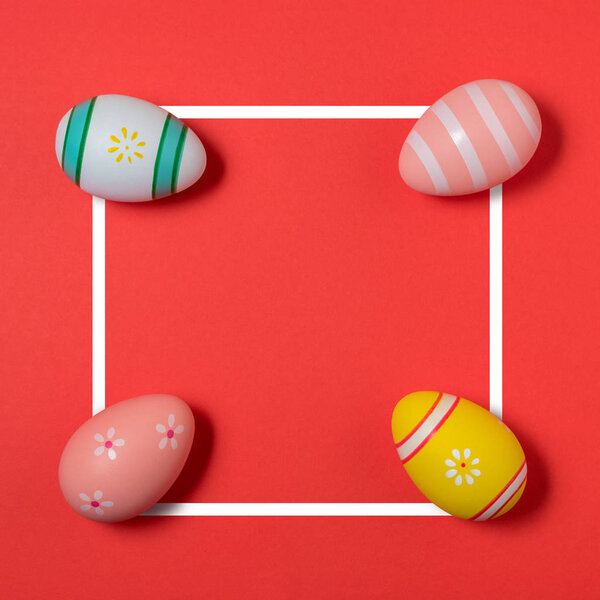 Creative Easter layout made of colorful eggs on red background. 