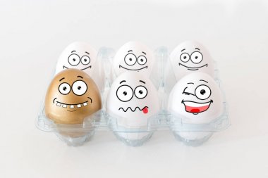 Komik yüzü olan bir altın ve beyaz yumurta