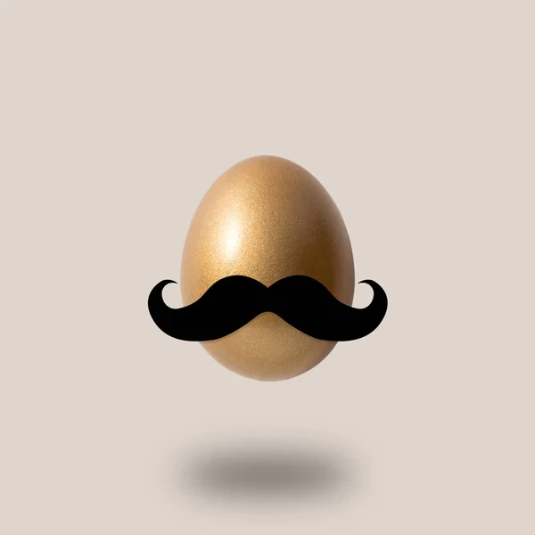 Huevo dorado con bigote sobre fondo brillante —  Fotos de Stock