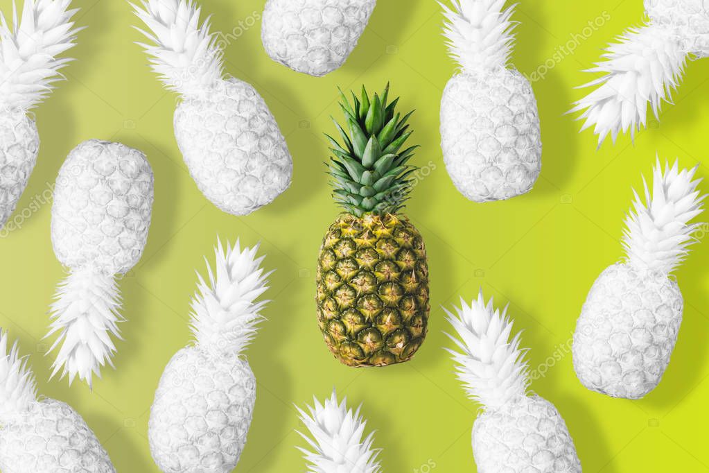 White colored pineapples on a vivid yellow background. 