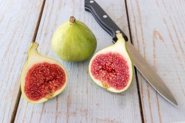 Yarım bir bahçe masa üstünde bütün incir ve bir incir dilimlenmiş. Dilimlenmiş incir üzerinde odaklanmıştır.