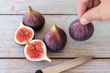 dilimlenmiş bir incir ahşap bir masa üzerinde tutan adamın el