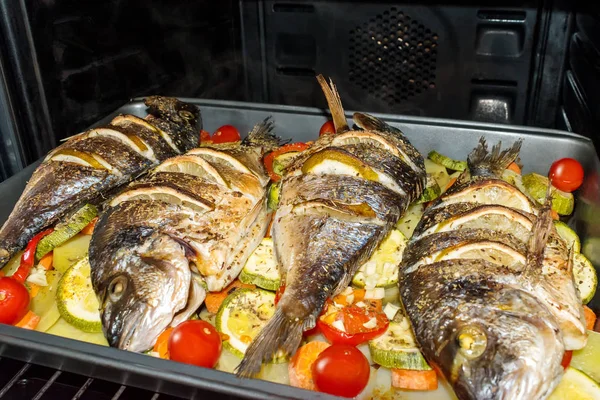 Baked dorada fish with vegetables and lemon in the oven. — Stock Photo, Image