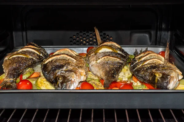 Roasted dorada fish with vegetables and lemon in the oven. — Stock Photo, Image