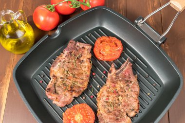 Koyu arka plan üzerinde domates ızgara tava üzerinde ızgara biftek 