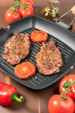 Koyu arka plan üzerinde domates ızgara tava üzerinde ızgara biftek 