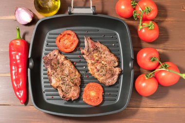 Koyu arka plan üzerinde domates ızgara tava üzerinde ızgara biftek 