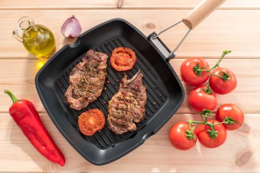 Ahşap zemin üzerine domatesli ızgara tava üzerinde ızgara biftek