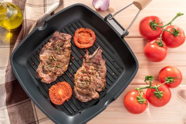 Ahşap zemin üzerine domatesli ızgara tava üzerinde ızgara biftek