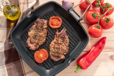 Ahşap zemin üzerine domatesli ızgara tava üzerinde ızgara biftek